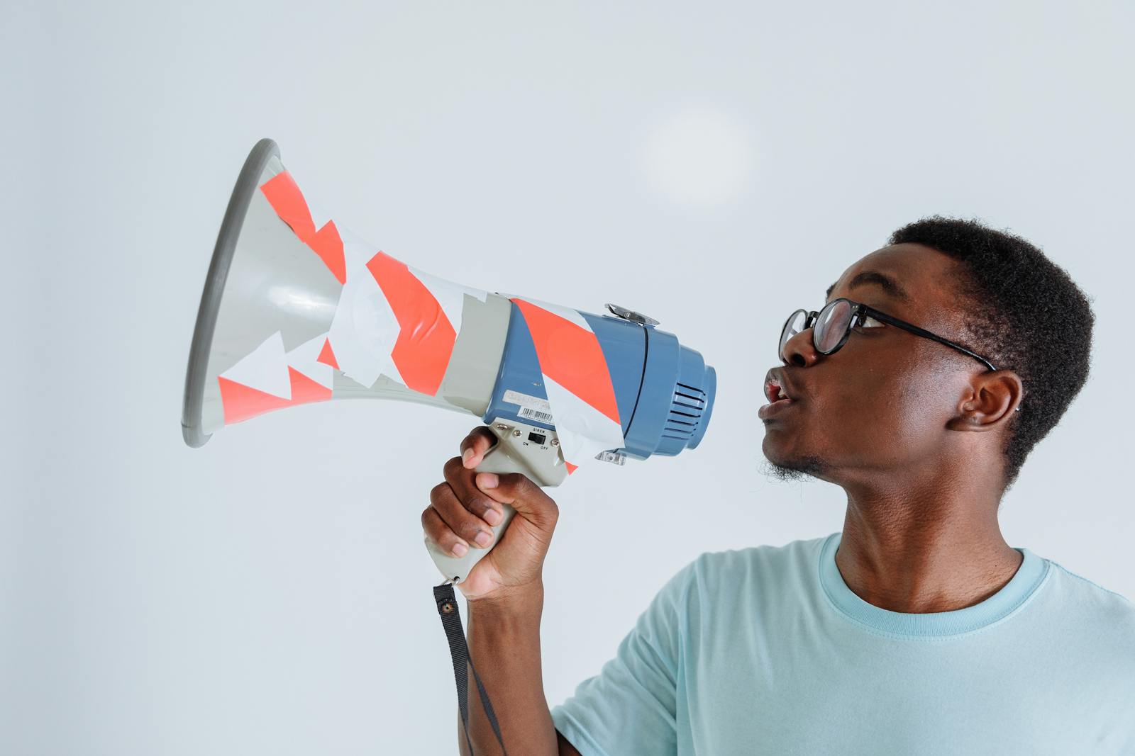 A young Black man holding a megaphone, raising his voice for a protest.