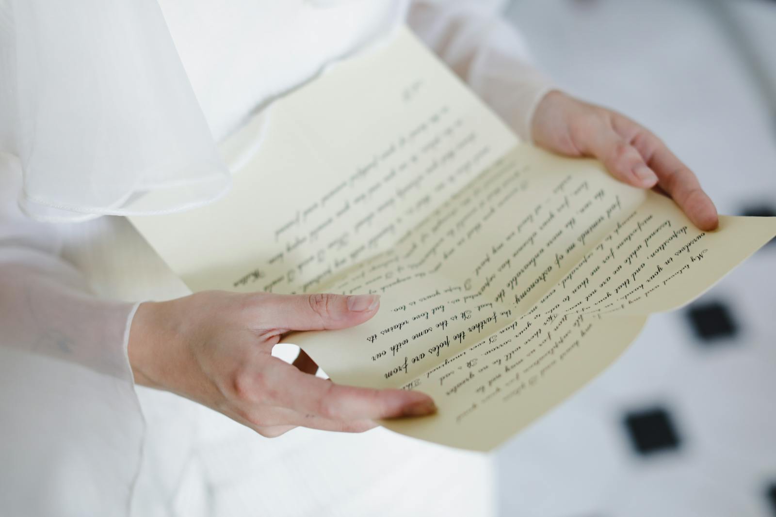 Close-up of hands delicately holding a handwritten letter with calligraphy.