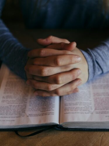 Photo by Patrick Fore man holding his hands on open book